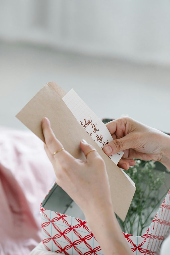 Close-up of hands holding a greeting card in an envelope with decorative wrapping.